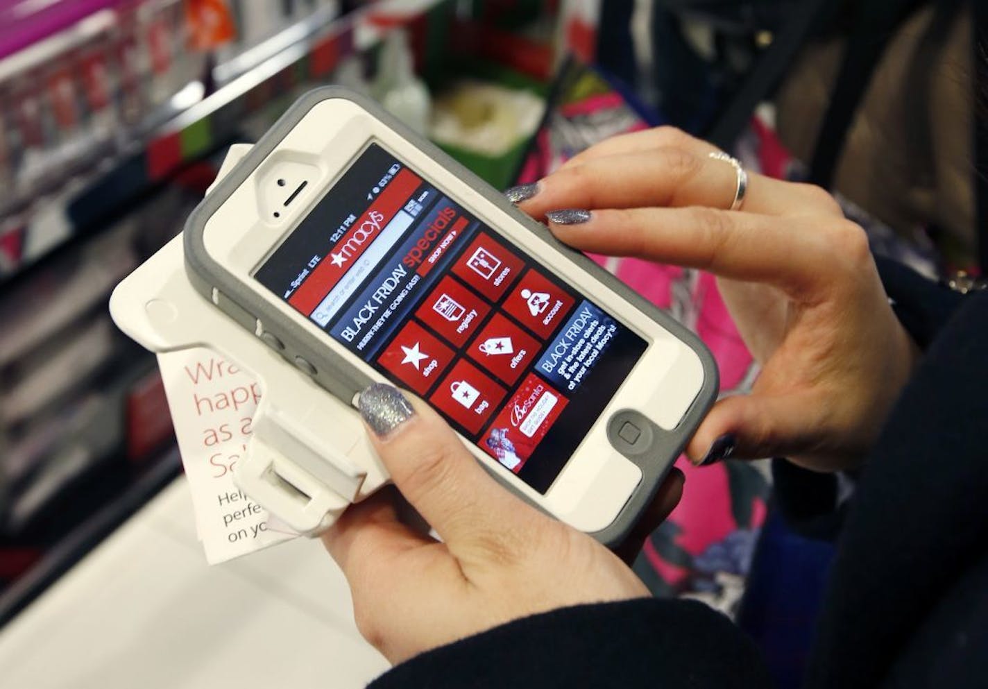 FILE - In this Friday, Nov. 23, 2012, file photo, Tashalee Rodriguez, of Boston, uses a smartphone app while shopping at Macy's in downtown Boston. Shoppers are flocking online Monday, Nov. 28, 2016, as �Cyber Monday� sales hit their peak. Each year, during the busy holiday shopping weekend that kicks off on Thanksgiving and the Friday after, known as Black Friday, more and more shoppers decide to skip the mayhem in stores and shop online.