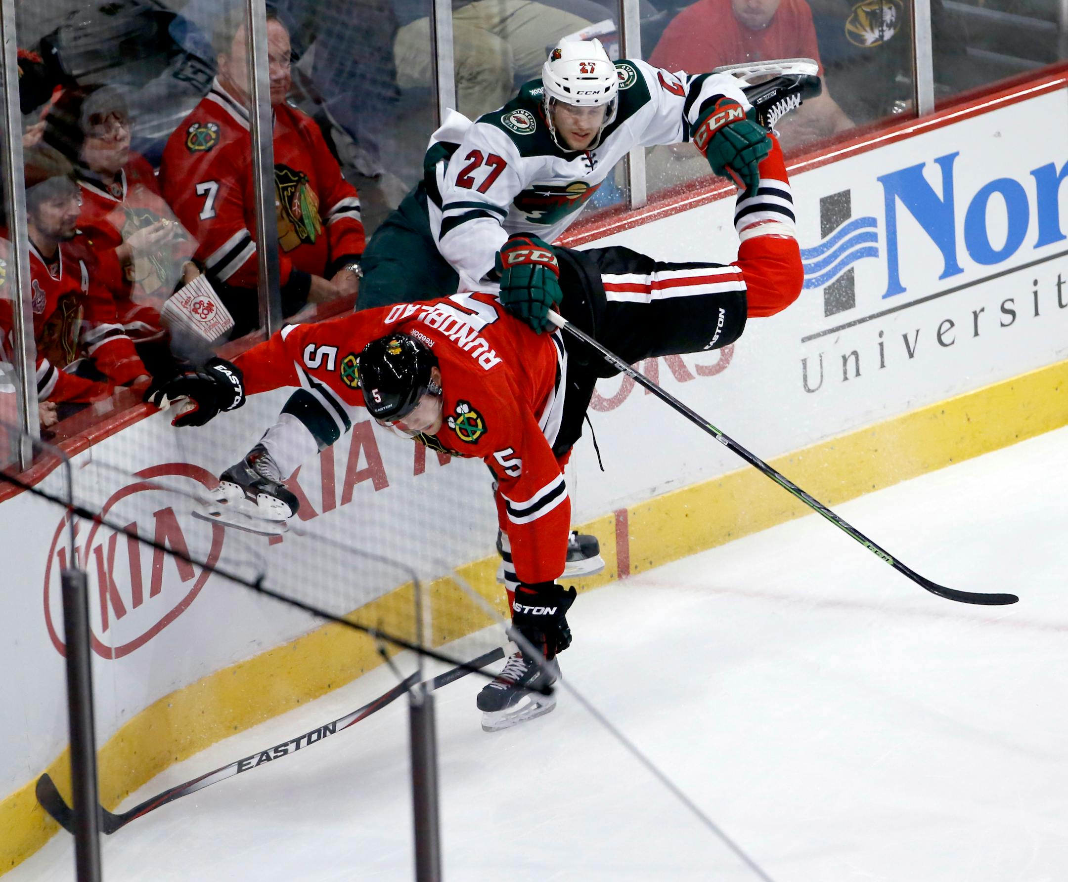 Wild center Brett Sutter (27) checked Blackhawks defenseman David Rundblad during the second period Tuesday. Sutter made his Wild debut against Chicago. His father, Kings coach Darryl Sutter, used to coach the Blackhawks and spent his entire playing career with Chicago.
