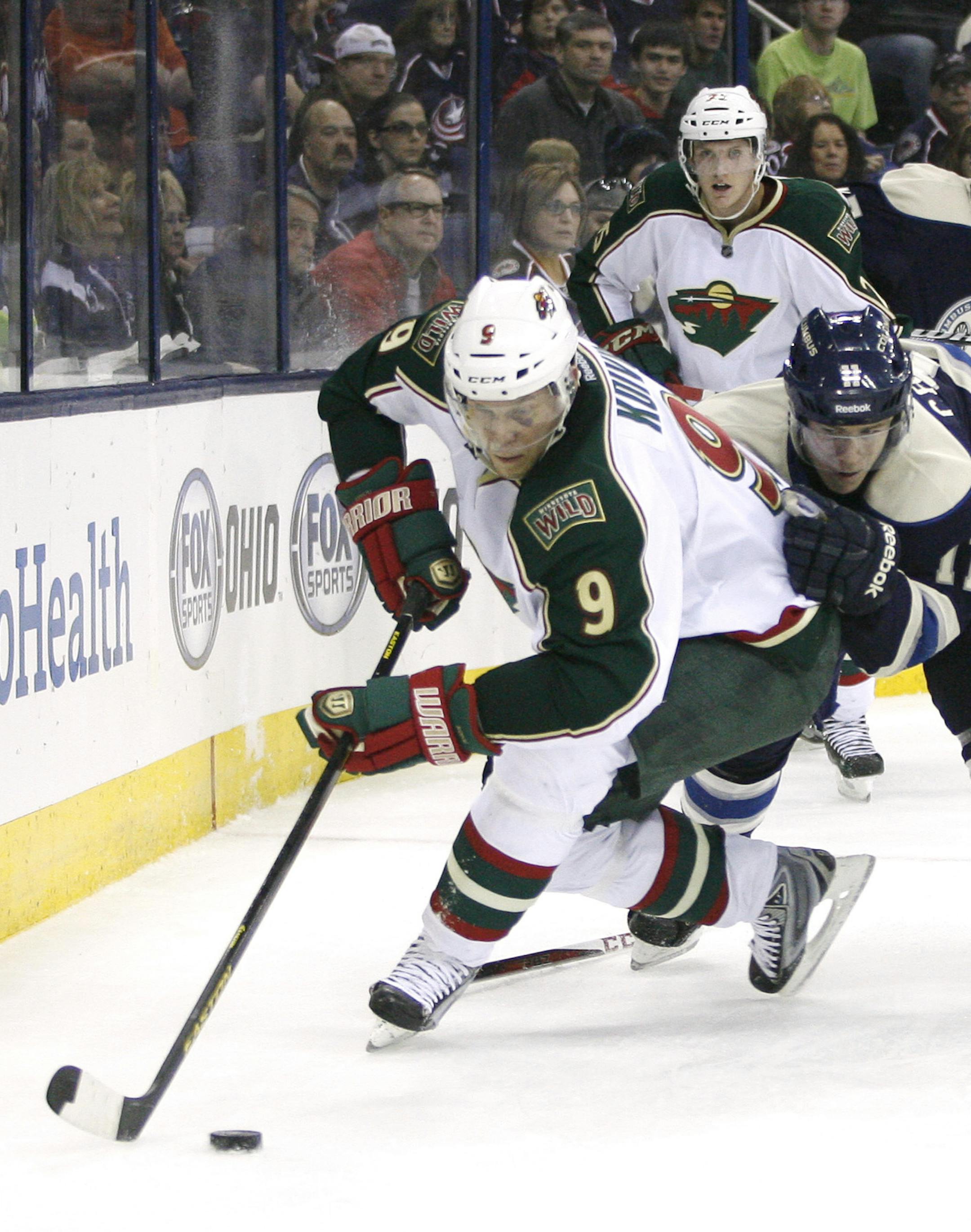 Columbus Blue Jackets' Matt Calvert (11), right, grabs the jersey of Minnesota Wild's Mikko Koive (9), of Finland, in the second period of an NHL hockey game on Sunday, April 7, 2013, in Columbus, Ohio. (AP Photo/Mike Munden)