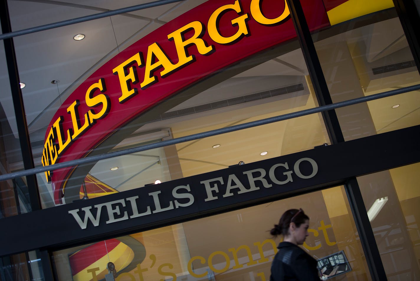 Pedestrians pass in front of a Wells Fargo & Co. bank branch in New York.