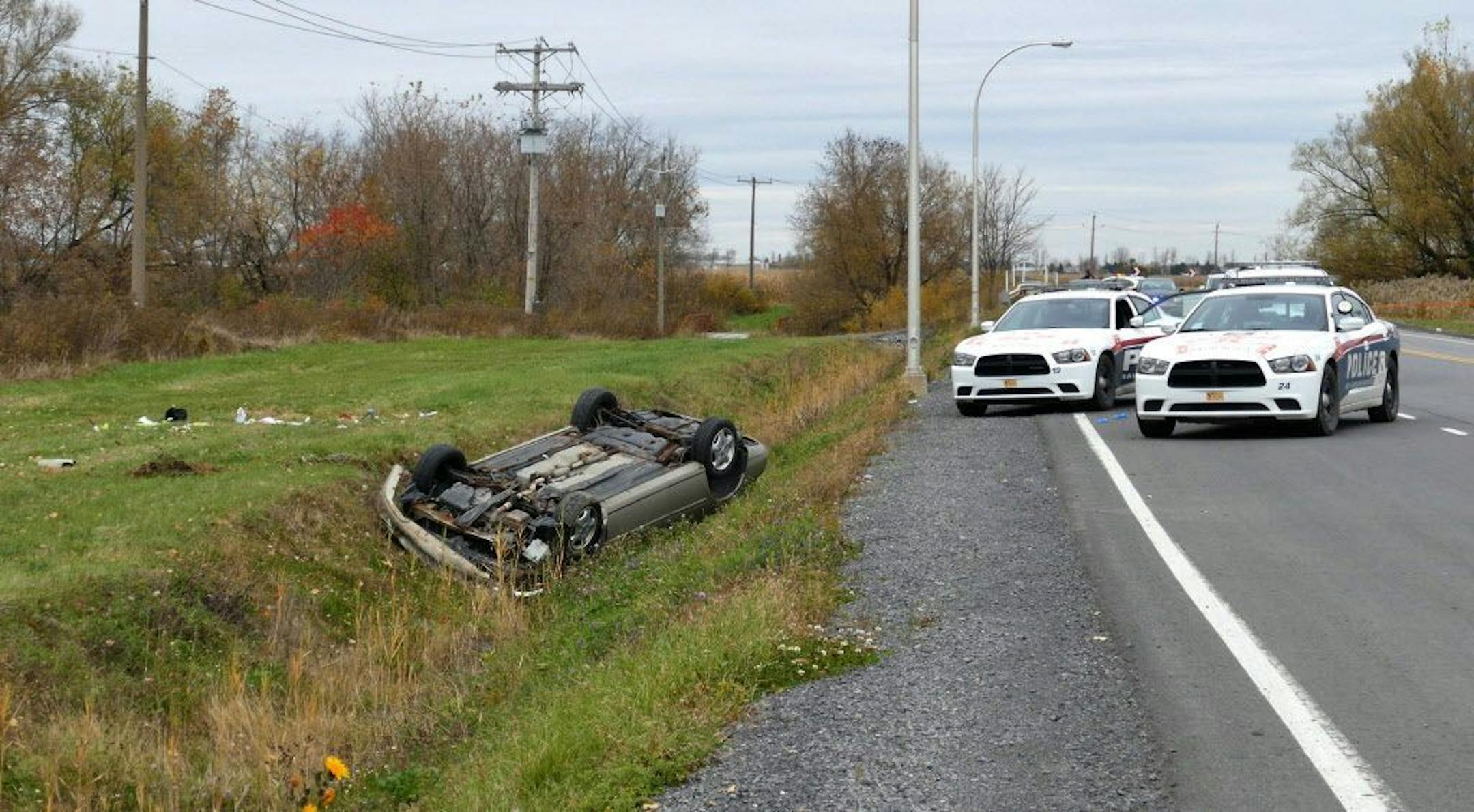 In a Monday Oct. 20, 2014 photo, a car is overturned in a ditch in a cordoned off area in St-Jean-sur-Richelieu, Quebec. One of two soldiers hit by a car on Monday in Saint-Jean-sur-Richelieu, Que., died of his injuries early Tuesday.