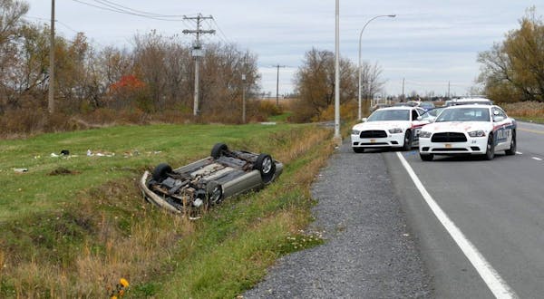 In a Monday Oct. 20, 2014 photo, a car is overturned in a ditch in a cordoned off area in St-Jean-sur-Richelieu, Quebec. One of two soldiers hit by a 