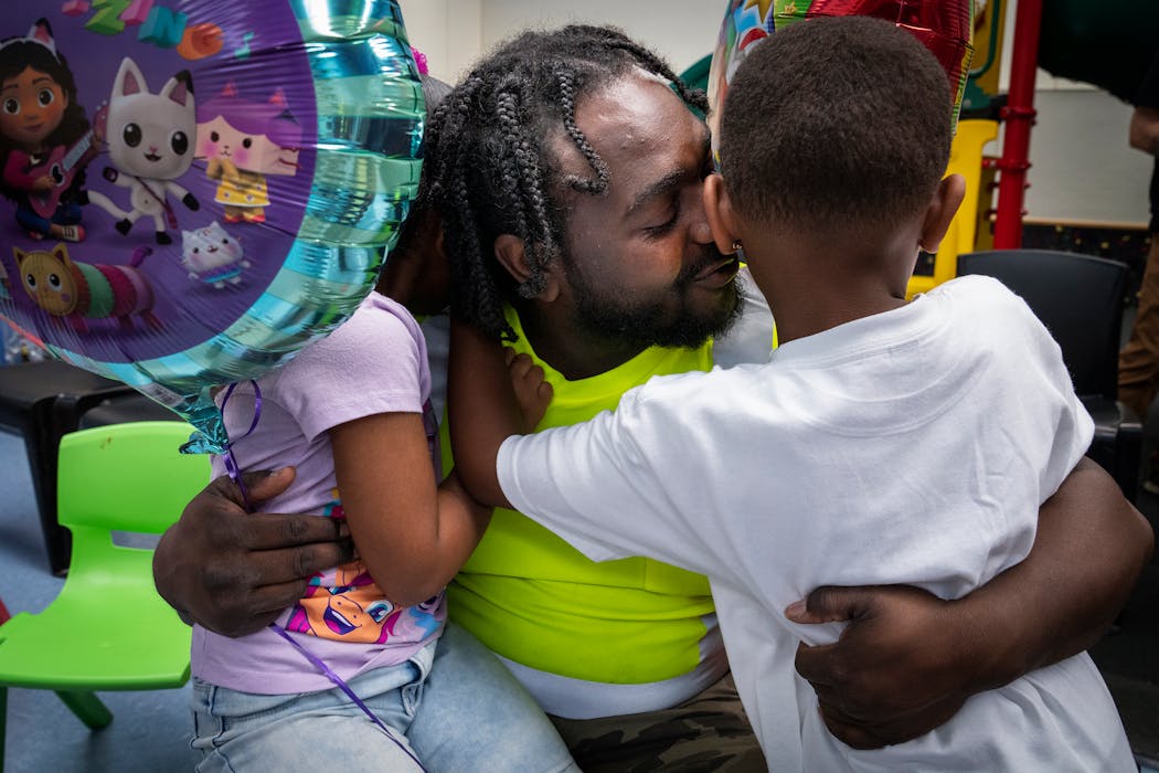 Keyowa King, center, hugs his son Kacyn King, right, who just graduated from preschool, while also holding his 4-year-old daughter Kira King after Kacyn’s graduation ceremony.