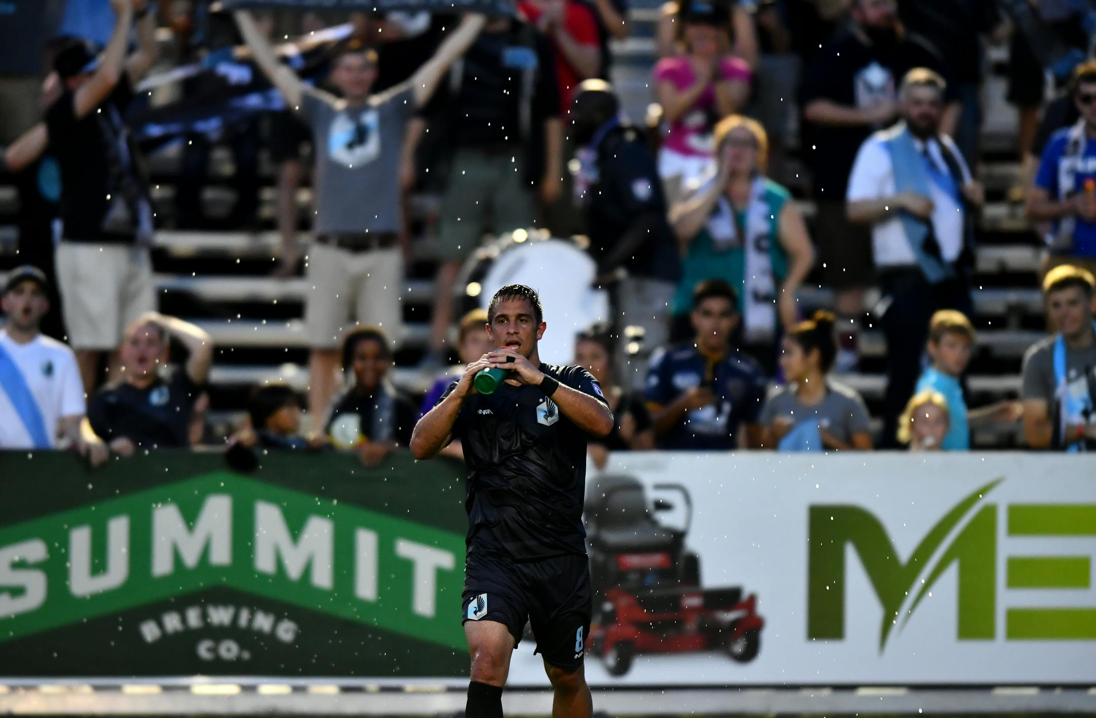 Minnesota United FC forward Danny Cruz (8) sprayed water in the air after celebrating with United fans after a win in July.