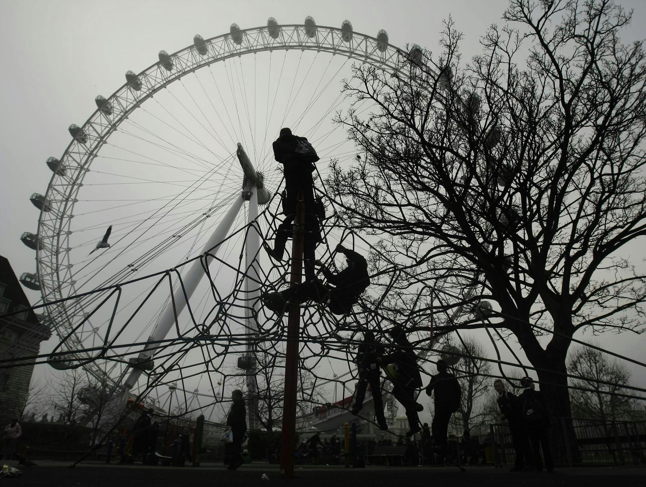 Youngsters are silhouetted as they play in a park as fog is seen over the London Eye ferris wheel in London, Tuesday Dec. 16, 2008. (AP Photo/Matt Dunham)