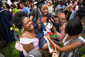 Champlin Park High School graduate Ashely Nyamari is lifted up by her aunts Damaris Ouru, left, and Elinnah Marube, and her mother, Sarah Okindo, duri