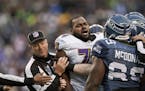 Michael Oher, then an offensive lineman for the Baltimore Ravens, was held back by an official as he tangled with Seattle players in a 2012 game.