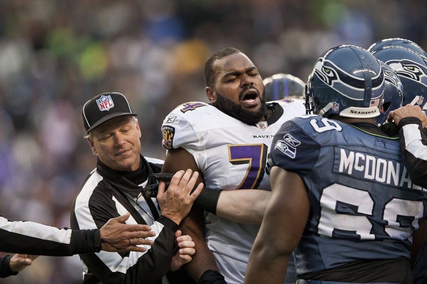 Michael Oher, then an offensive lineman for the Baltimore Ravens, was held back by an official as he tangled with Seattle players in a 2012 game.