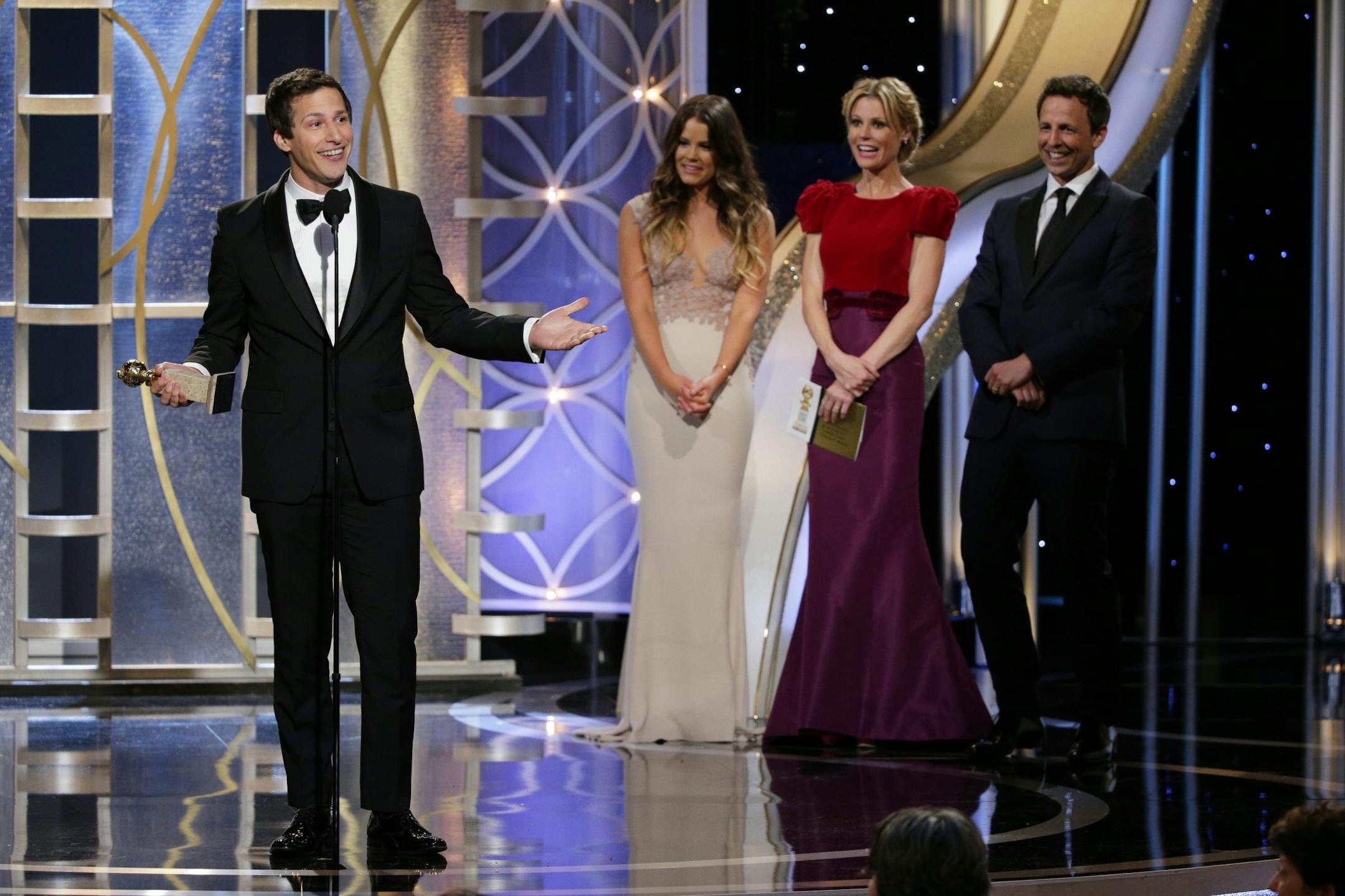 This image released by NBC shows Andy Samberg accepting the award for best actor in a TV comedy series for his role in "Brooklyn Nine-Nine," as, from second left, Sosie Bacon, and presenters Julie Bowen and Seth Meyers look on during the 71st annual Golden Globe Awards at the Beverly Hilton Hotel on Sunday, Jan. 12, 2014, in Beverly Hills, Calif.