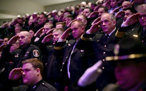 Members of law enforcement salute as the caskets representing the fallen as they are brought into the sanctuary at Grace Church at the start of the me