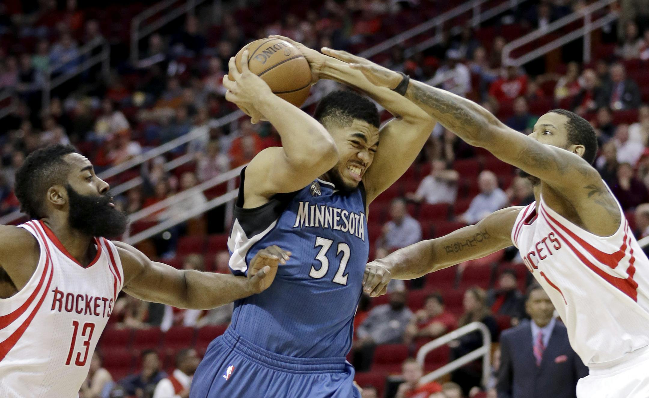 The Timberwolves' Karl-Anthony Towns (32) goes up for a shot as Houston Rockets' Trevor Ariza (1) and James Harden (13) defend in Houston.