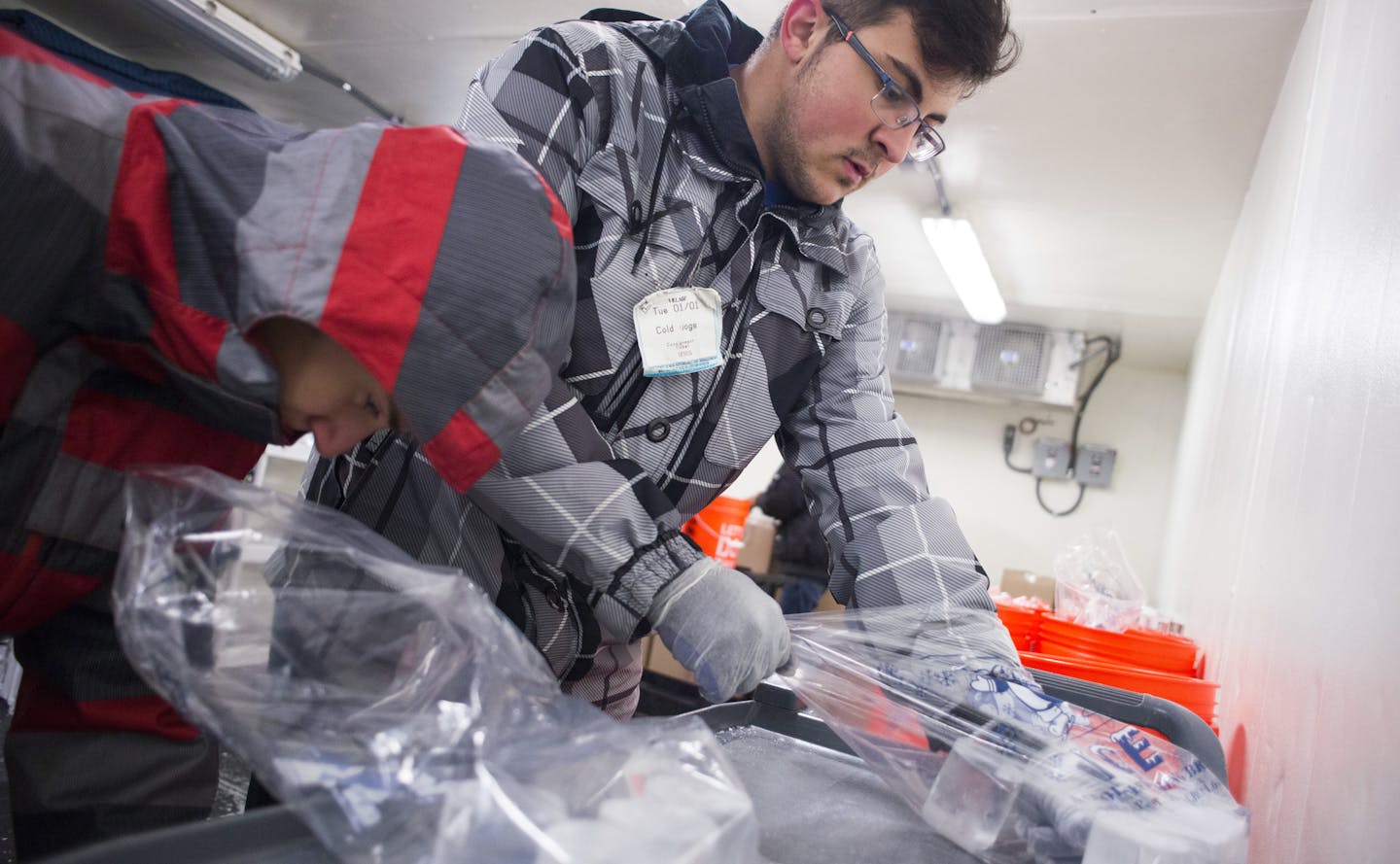 Dane Okerstrom, left, and Charbel Estephan bag ice in Minnesota Ice's walk-in cooler space. The company's ice is used in cocktails at Eat Street Social in Minneapolis.