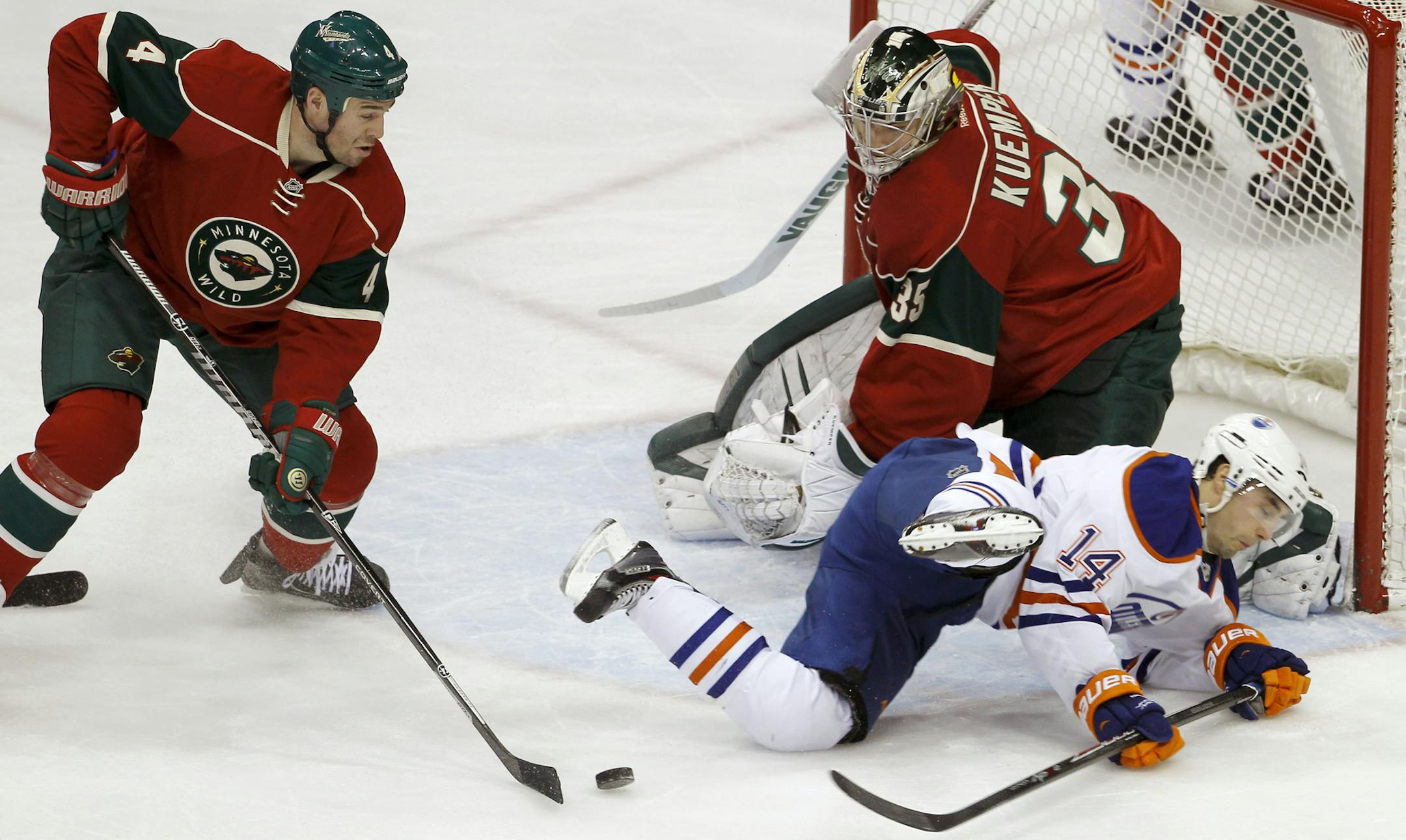 Minnesota Wild defenseman Clayton Stoner, left, clears a rebound as Wild goalie Darcy Kuemper (35) covers the net and Edmonton Oilers right wing Jordan Eberle (14) falls during the first period of an NHL hockey game in St. Paul, Minn., Thursday, Jan. 16, 2014. (AP Photo/Ann Heisenfelt)
