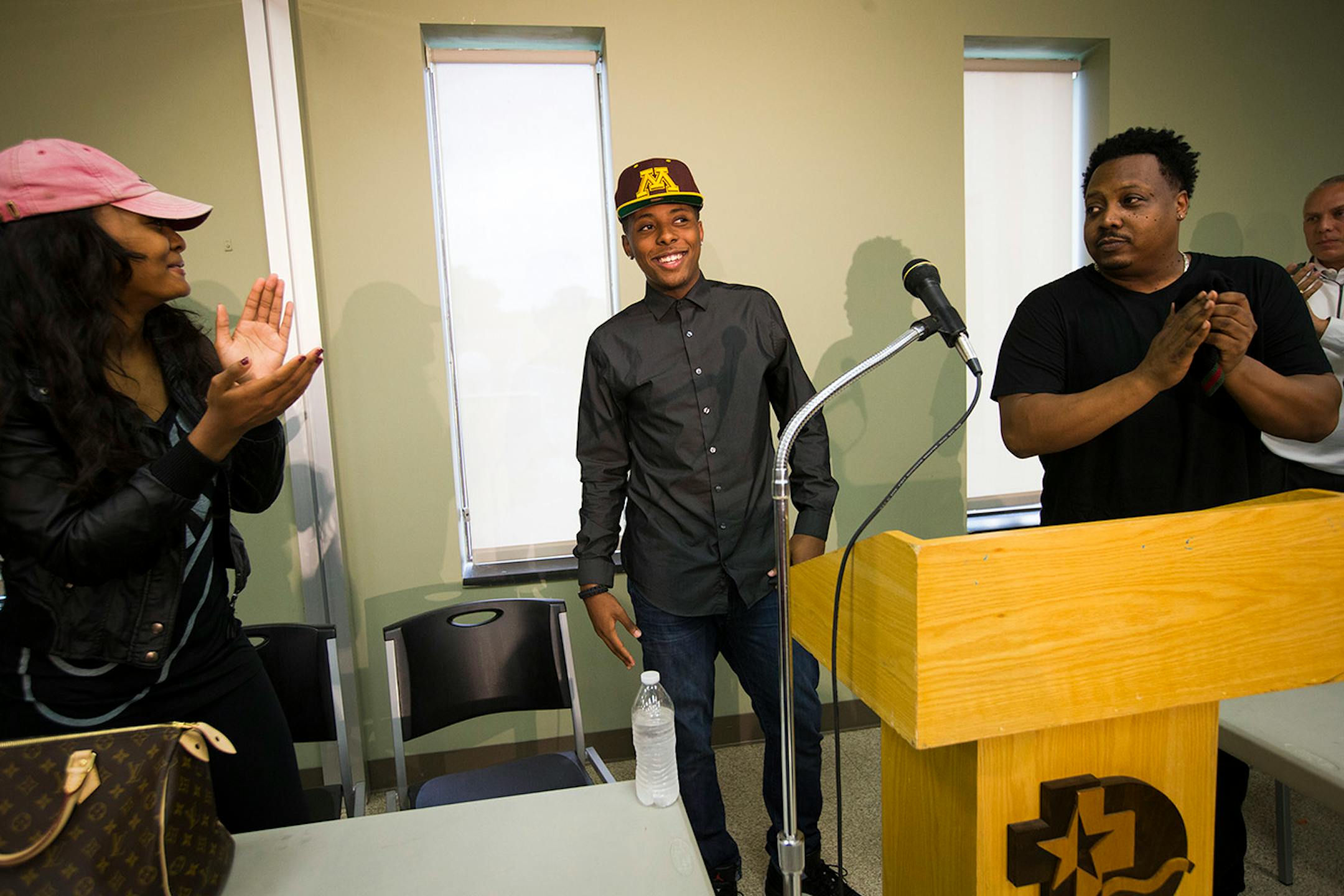 Surrounded by his family, Jarvis Johnson, DeLaSalle basketball star, put on a Gopher's hat as he announced his college choice of the University of Minnesota at DeLaSalle High School on Friday, Sept. 12, 2014, in Minneapolis, Minn. ] RENEE JONES SCHNEIDER • reneejones@startribune.com