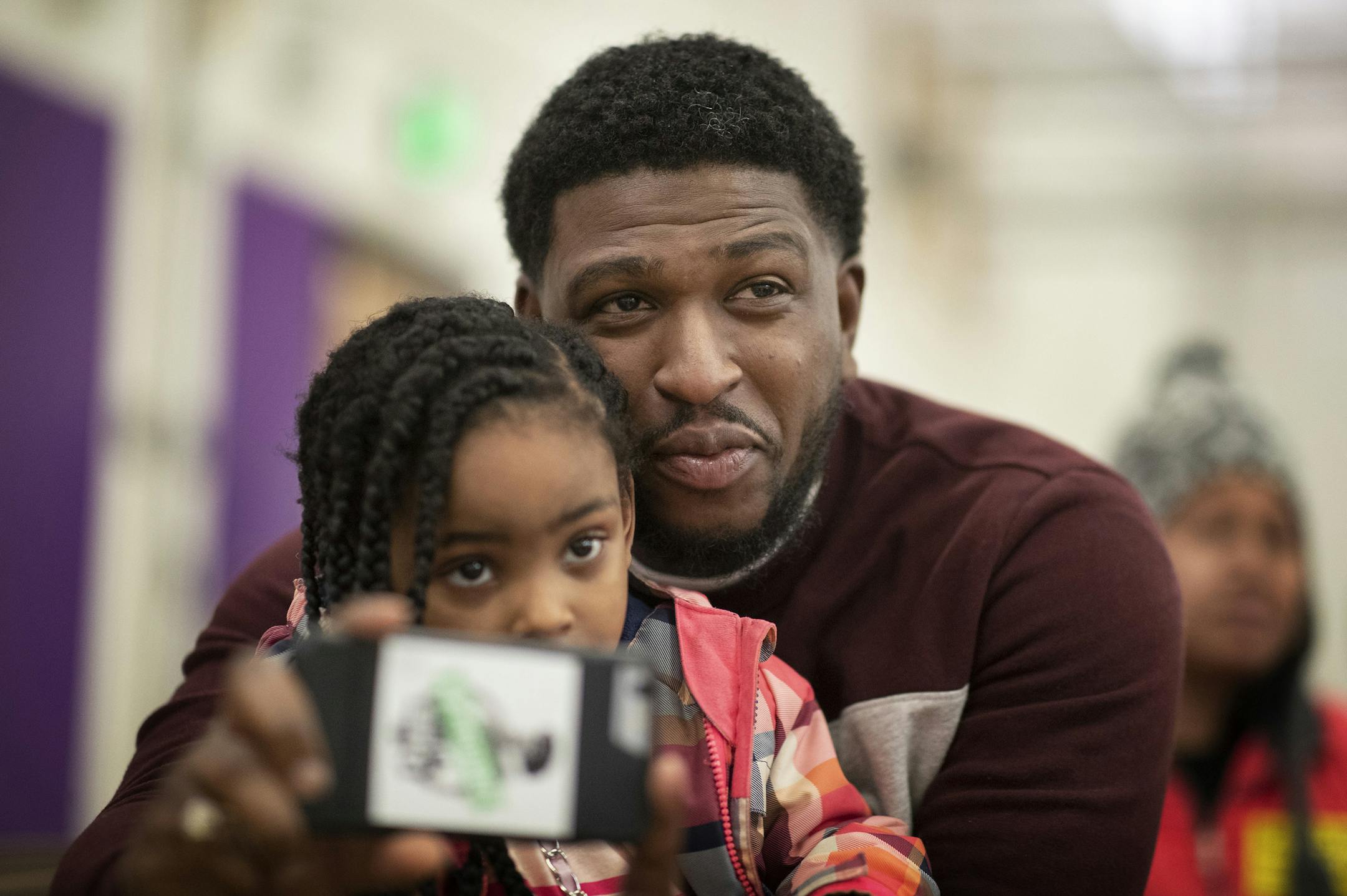 Charlie Lee held his 4-year-old daughter Nellie as he recorded his fourth-grader, Niyah, on Monday, Feb. 10, at St. Paul's Galtier Community Elementary School. Niyah was performing as Rosa Park in a play about the Montgomery bus boycott.
