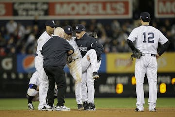 Trainer Steve Donohue, second from left, and New York Yankees manager Joe Girardi, second from right, help Derek Jeter off the field after he injured 