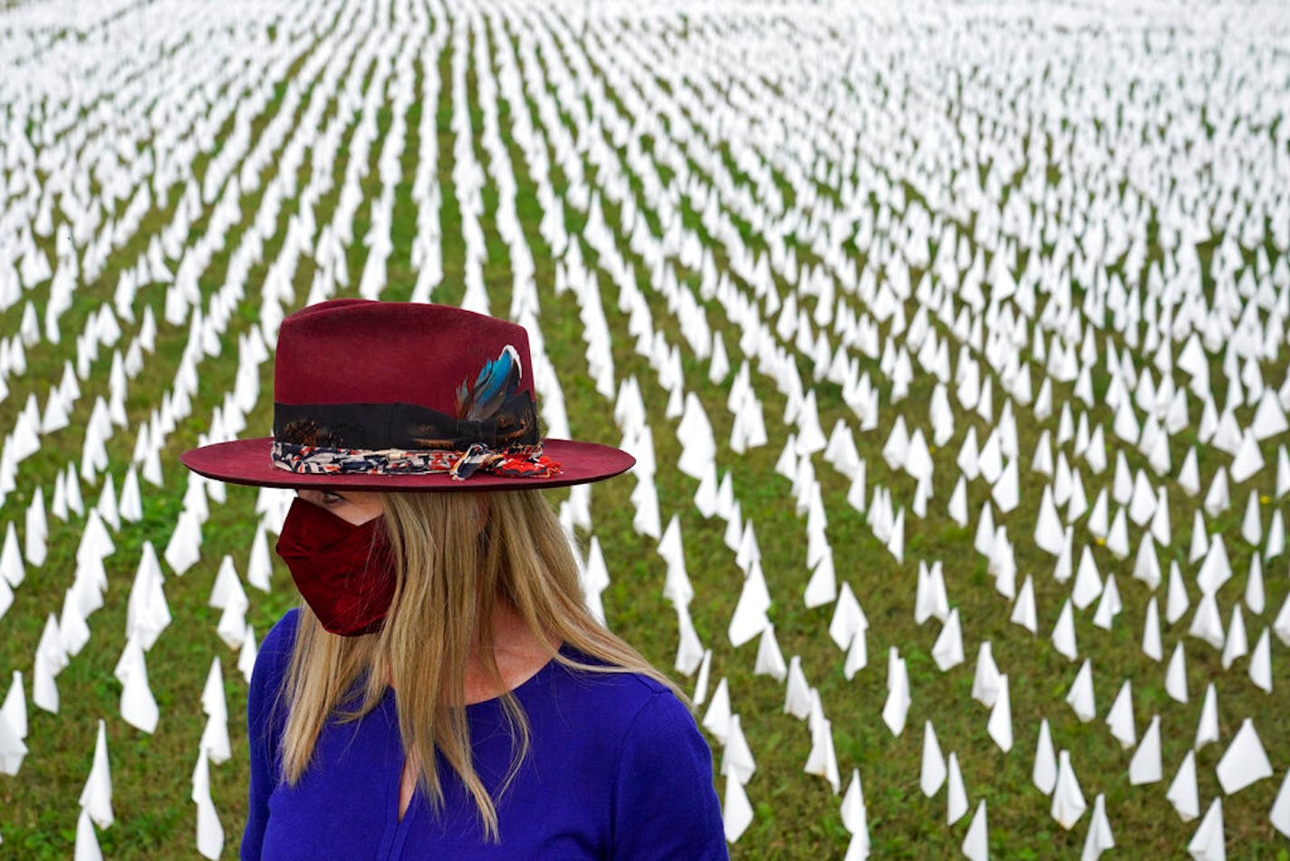 Artist Suzanne Brennan Firstenberg stands among thousands of white flags planted in remembrance of Americans who have died of COVID-19, Tuesday, Oct. 27, 2020, near Robert F. Kennedy Memorial Stadium in Washington. Firstenberg's temporary art installation, called "In America, How Could This Happen," will include an estimated 240,000 flags when completed.