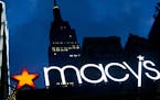 FILE - In this Nov. 21, 2013, file photo, with the Empire State building in the background, the Macy's logo is illuminated on the front of the departm