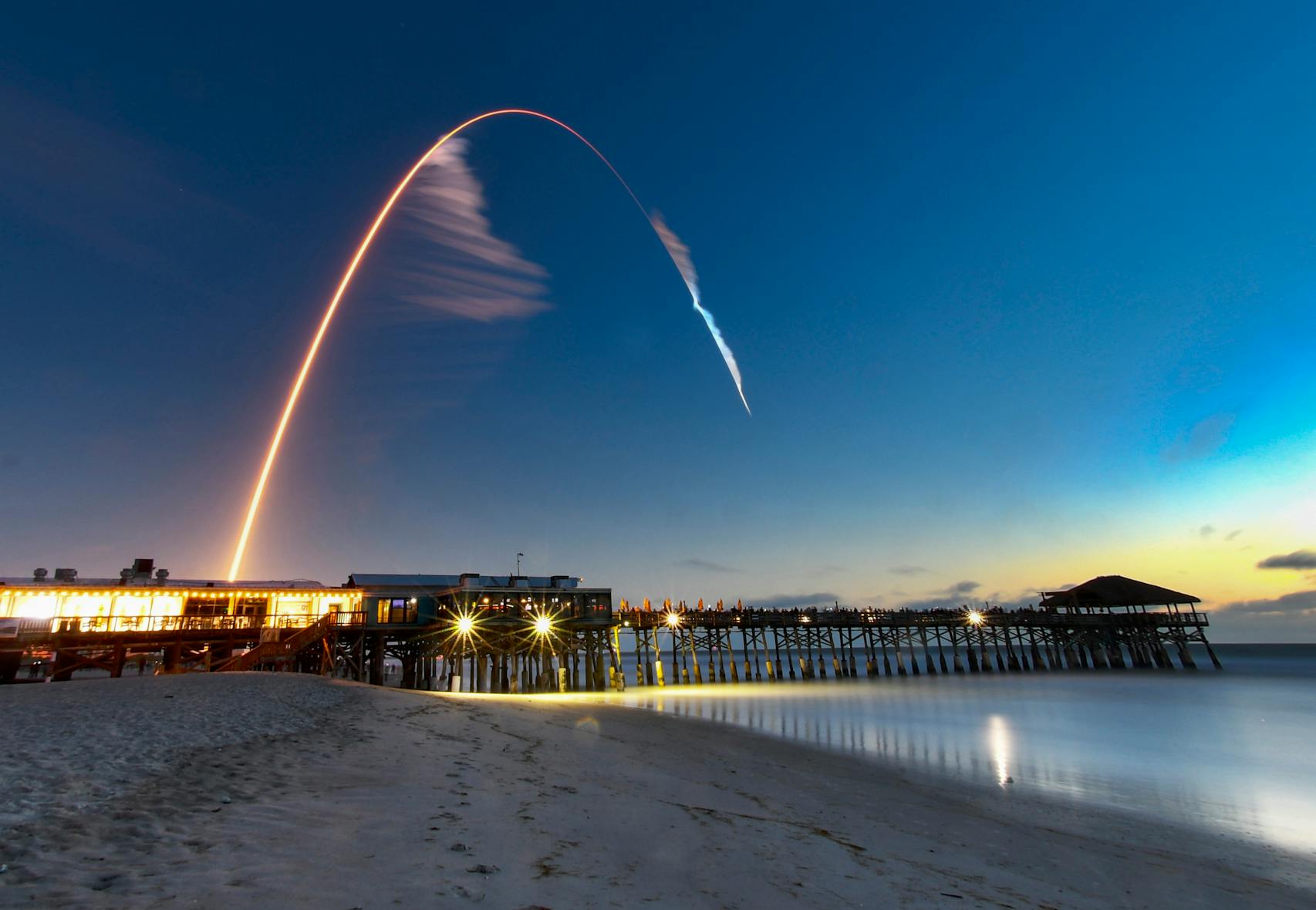 A United Launch Alliance Atlas V rocket lifts off at Cape Canaveral with the Cocoa Beach, Fla., Pier in the foreground.