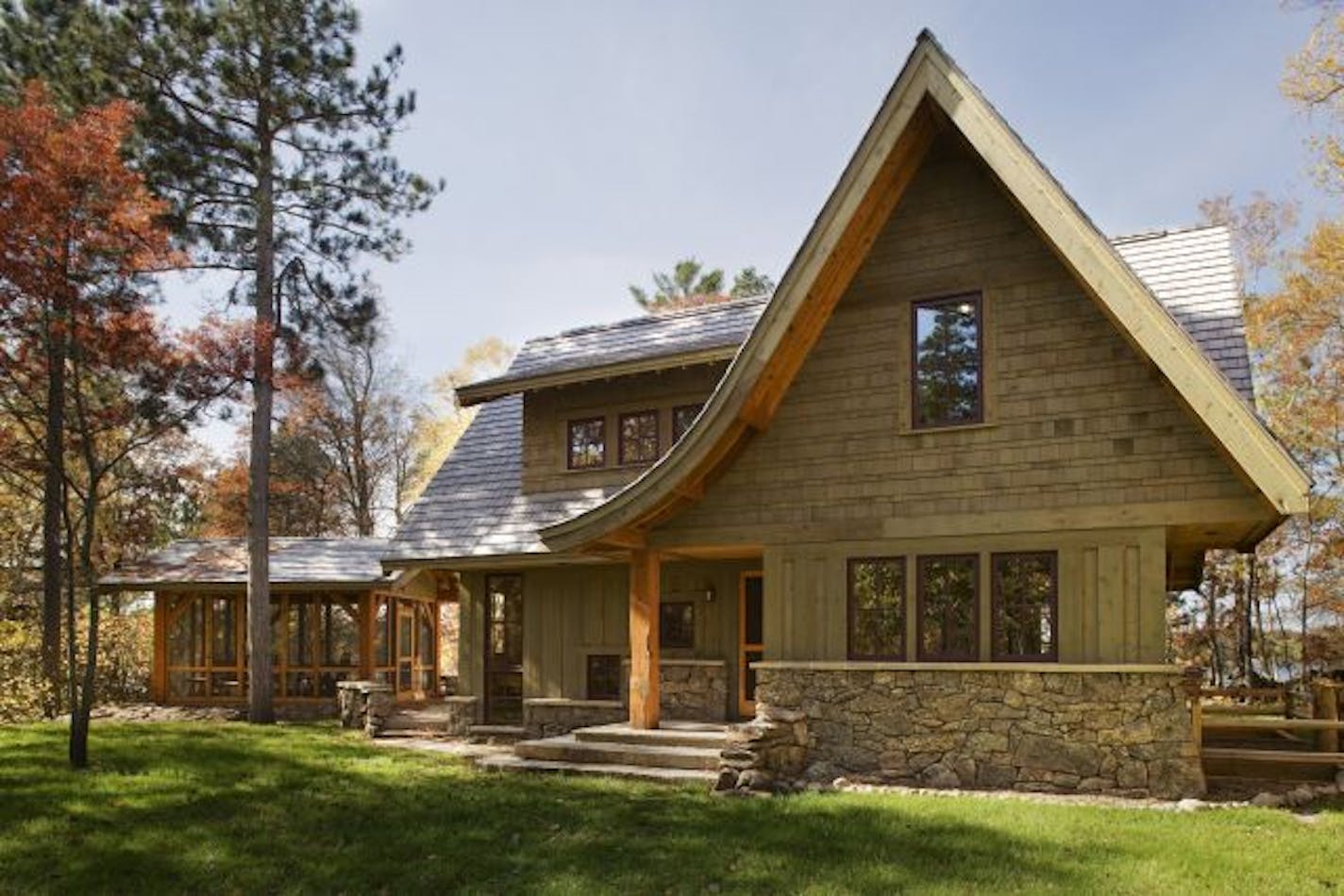 The entry side of the eco-friendly Lee lake home features a whimsical swooping roofline that softens the rugged stone and cedar exterior.