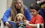 Kai Pat 7, read to Molly a Vizsla therapy dog, with her owner Connie Priesz at Cedar Ridge Elementary School Monday October 30,2017 in Eden Prairie, M