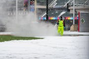 A worker used a hose to clear snow and ice Friday at Target Field in Minneapolis. The Twins postponed Friday's game because of the weather.