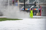 A worker used a hose to clear snow and ice Friday at Target Field in Minneapolis. The Twins postponed Friday's game because of the weather.