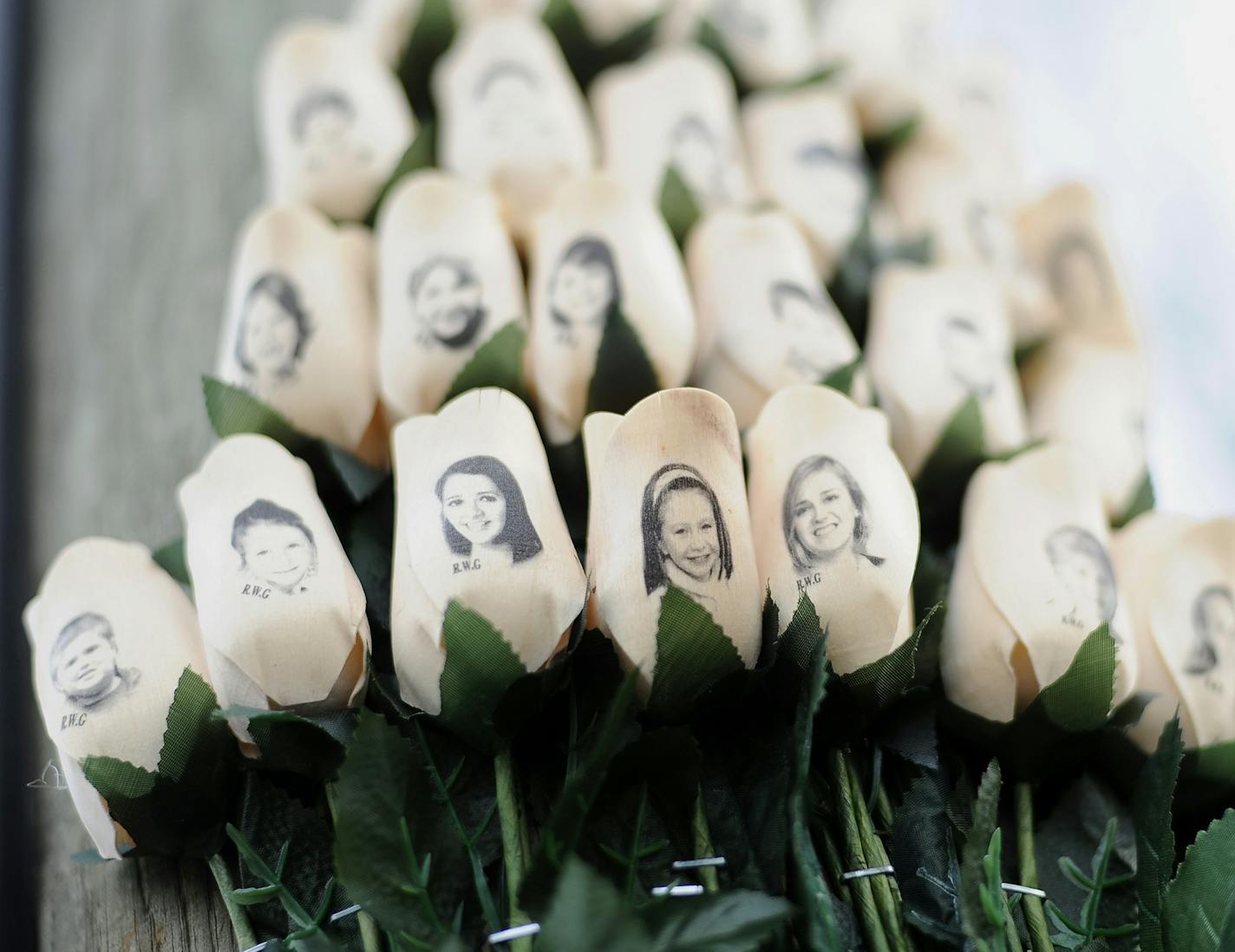 FILE - In this Jan. 14, 2013 file photo, white roses with the faces of victims of the Sandy Hook Elementary School shooting are attached to a telephone pole near the school on the one-month anniversary of the shooting that left 26 dead in Newtown, Conn. Some Newtown families have said they were given a voice late in the process of dispersing the millions of dollars in donated funds, and that the process has been bureaucratic, difficult, unpleasant, and has added to their pain. (AP Photo/Jessica