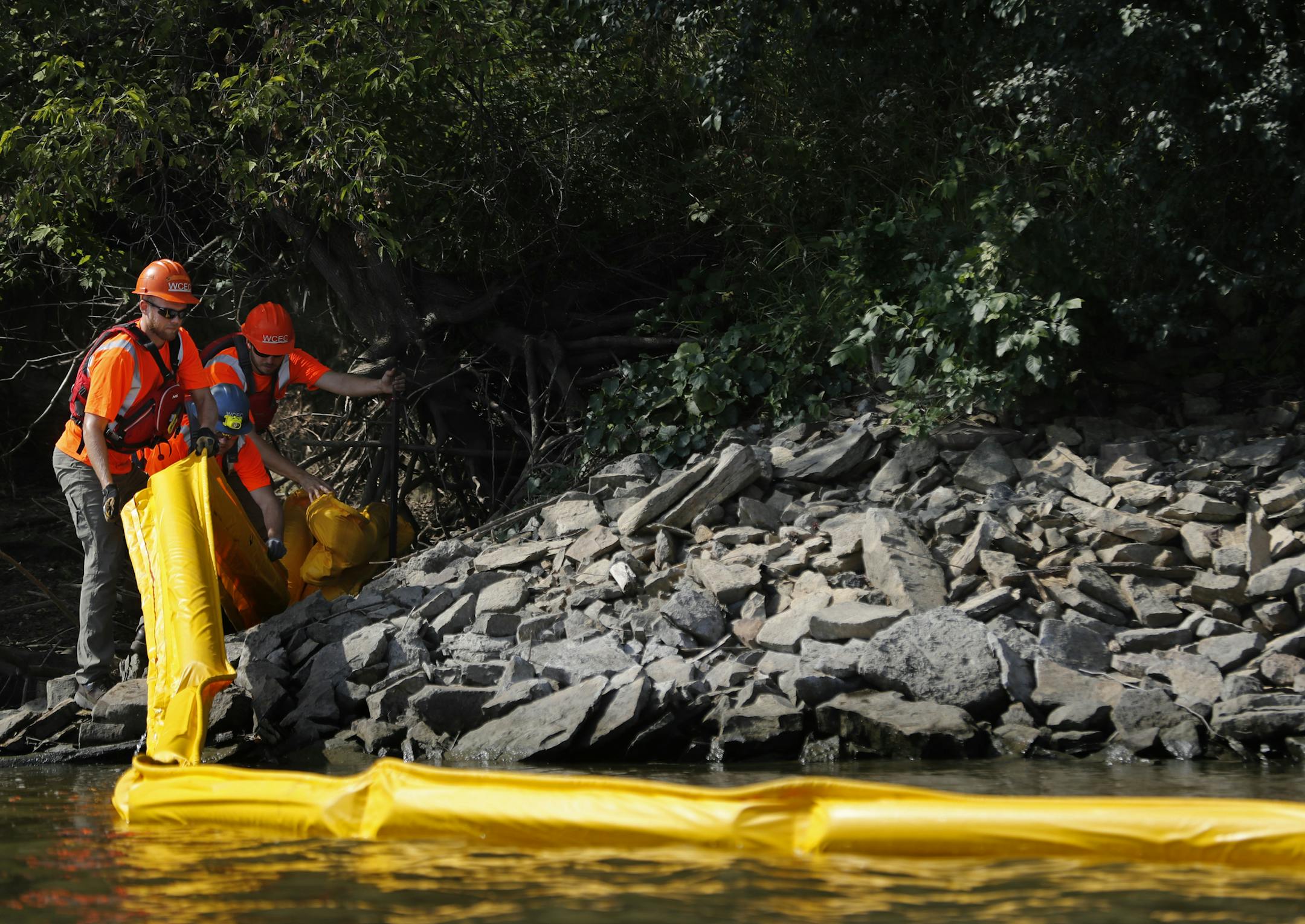 Members of West Coast Environmental Consultants Spill Team, a contractor used by railroads to help clean up environmental emergencies, practiced containing an oil spill using a boom and securing it to the shore of the Mississippi River.