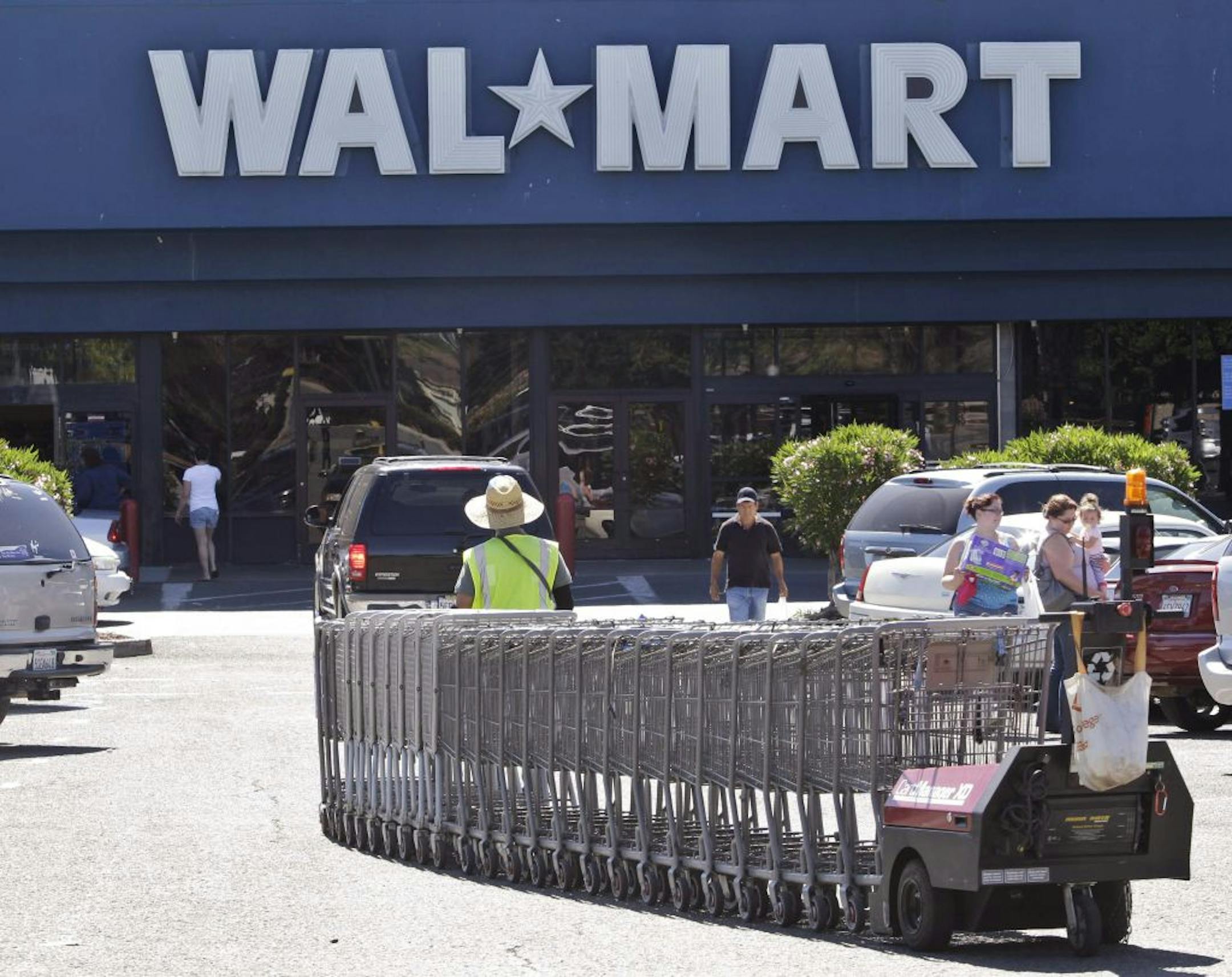 In this June 20, 2011 file photo, a Wal-Mart worker pulls carts at a Wal-Mart store in Pittsburg, Calif. A week before Halloween and two full months before Christmas, stores are desperately trying to outdo each other in hopes of drawing in customers worn down by the economy. Wal-Mart, the biggest store in the nation, joined the price wars Monday, Oct. 24, 2011, by announcing that it would give gift cards to shoppers if they buy something there and find it somewhere else cheaper.