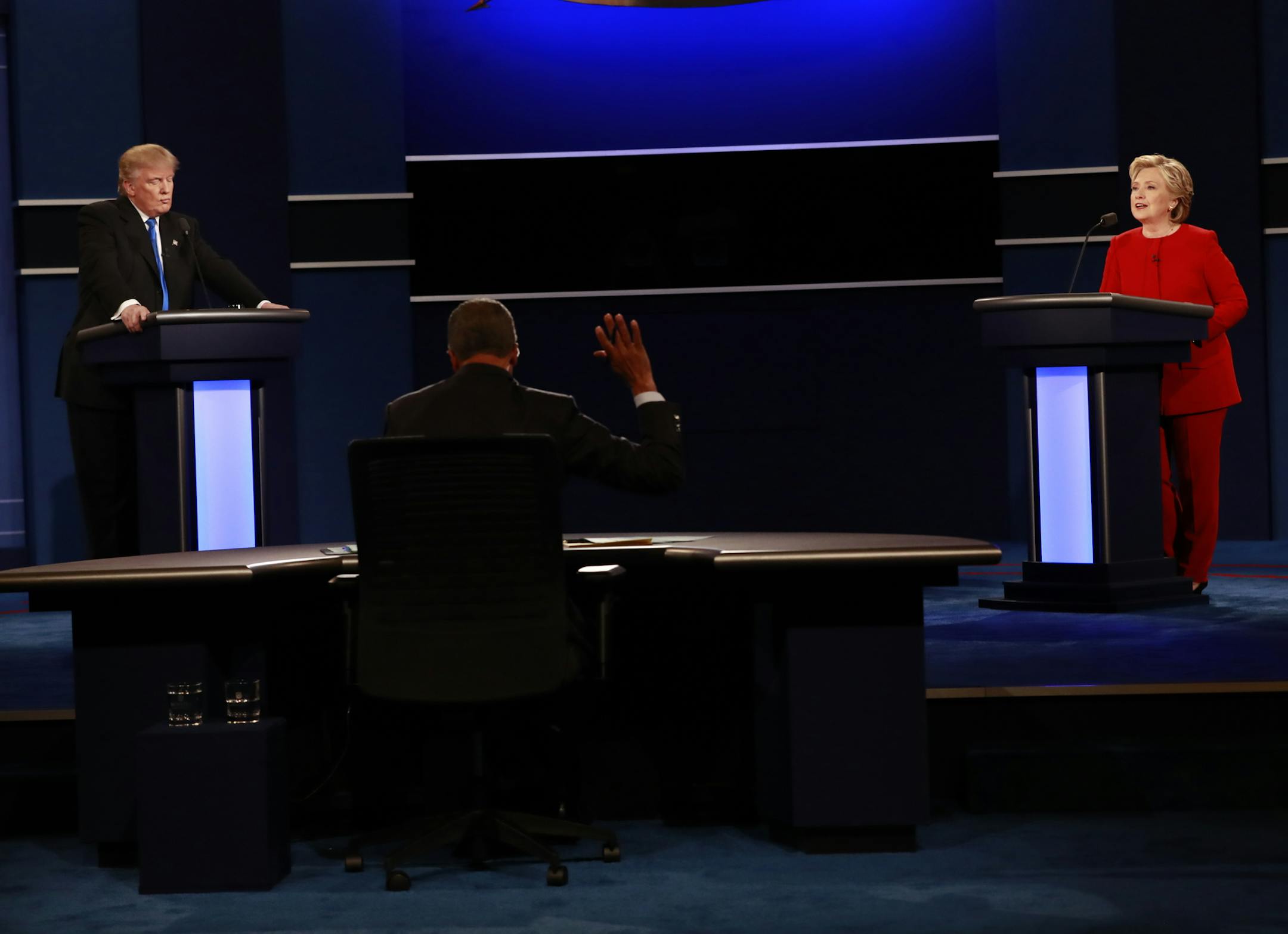 FILE -- Moderator Lester Holt raises a hand as Hillary Clinton and Donald Trump speak during the first presidential debate, at Hofstra University in Hempstead, N.Y., Sept. 26, 2016. Clinton’s campaign is preparing for the possibility that Trump, reeling from harsh criticisms of his performance at the first presidential debate, will unleash a personal assault related to her husband’s infidelities at their next face-off in a week. (Doug Mills/The New York Times)