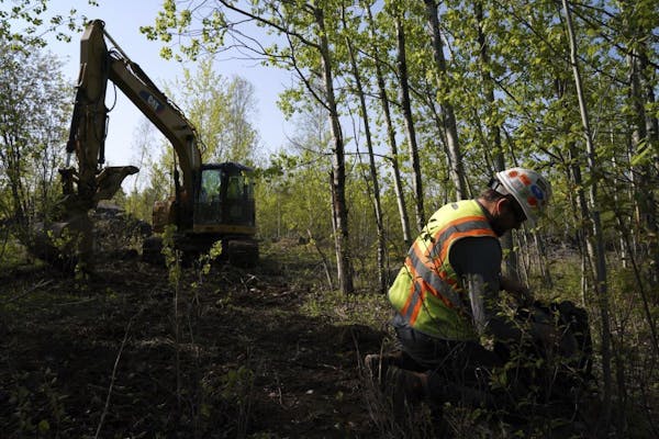 In this Wednesday, May 29, 2019, Eric Olson, right, gathers his tools as contractor Robert Radotich uses a backhoe to dig areas so the soil stratifica