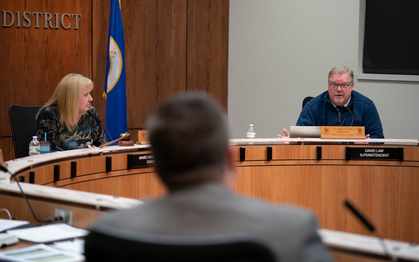 Man and woman sit at a dais in a board room