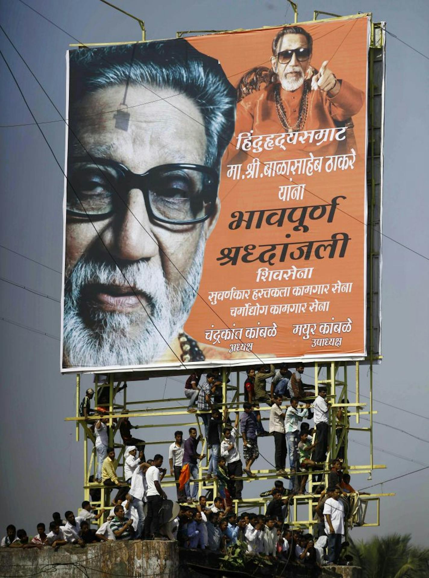 Indian mourners climb on a billboard of Hindu hardline Shiv Sena party leader Bal Thackeray during his funeral in Mumbai, India, Sunday.