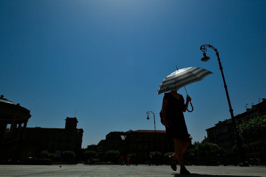 A woman shelters from the sun with an umbrella during a hot summer day, in Pamplona, northern Spain, Friday, June, 28, 2019