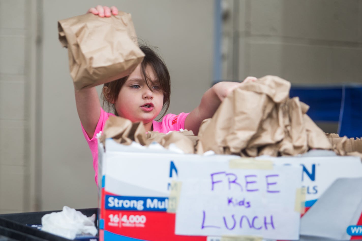 A child picks up a sack lunch on Monday, March 16, 2020, in Huntington, West Virginia. Businesses at The Market, in Huntington, bagged 250 free lunches for children who are out of school due to efforts to contain the spread of the coronavirus. (Ryan Fischer/The Herald-Dispatch via AP)