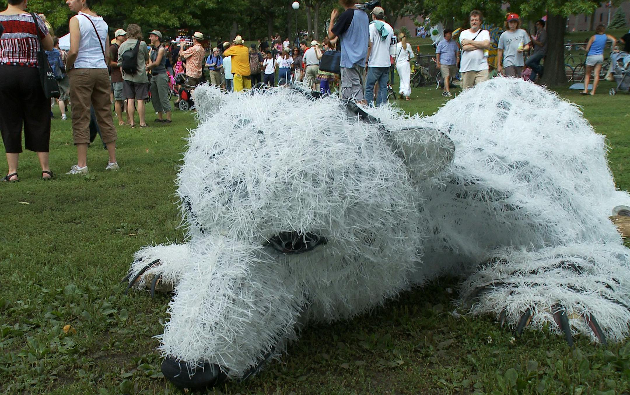 A polar bear that was part of the Liberty Parade sits on the ground after finishing its walk down Nicollette Ave as part of a support efforts on global warming and the possible demise of the Polar Bears.