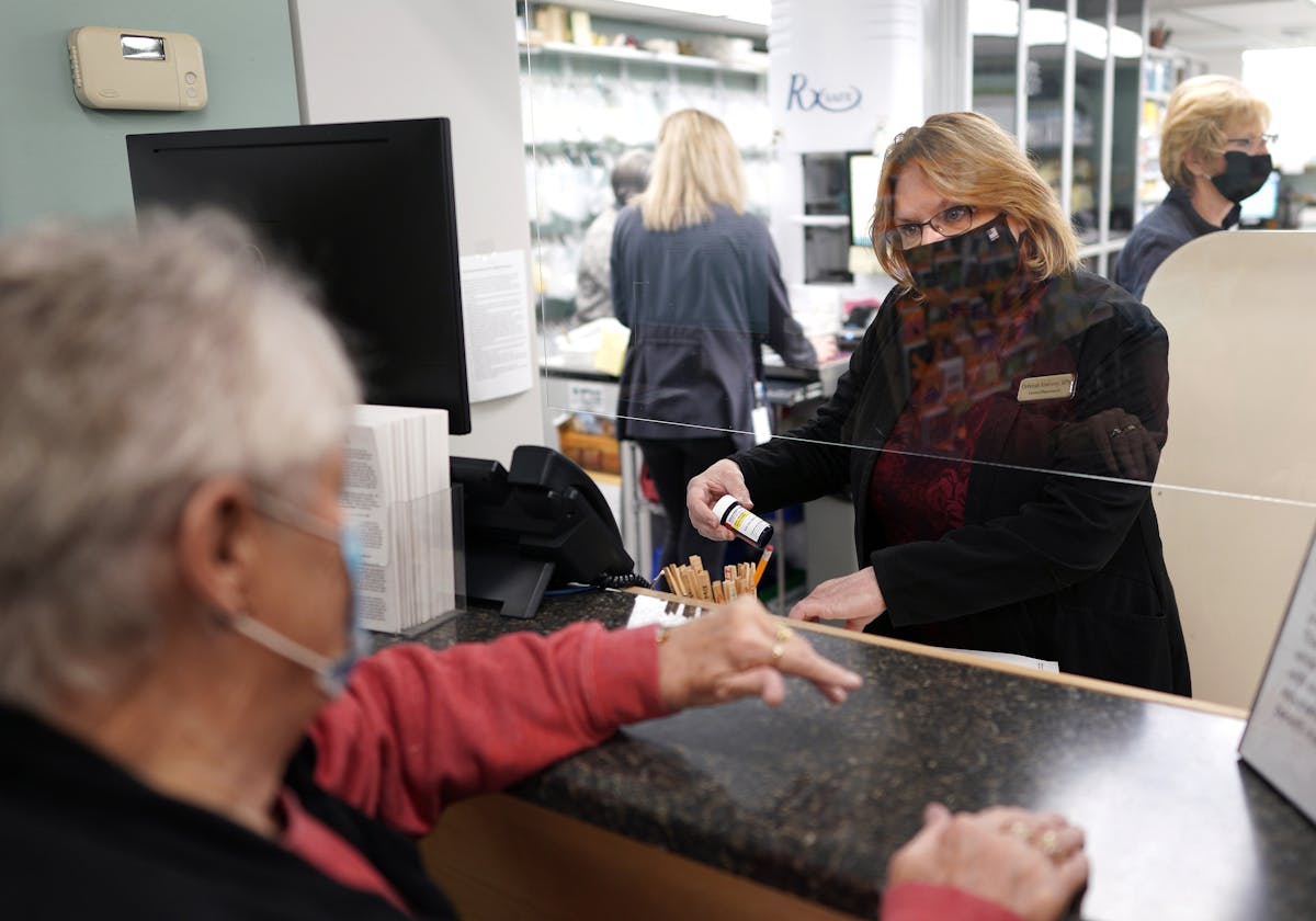 In this file photo from Oct. 21, 2020, Deb Keaveny, a pharmacist at Keaveny Drug, fills a prescription for a Winsted resident and long time customer. 