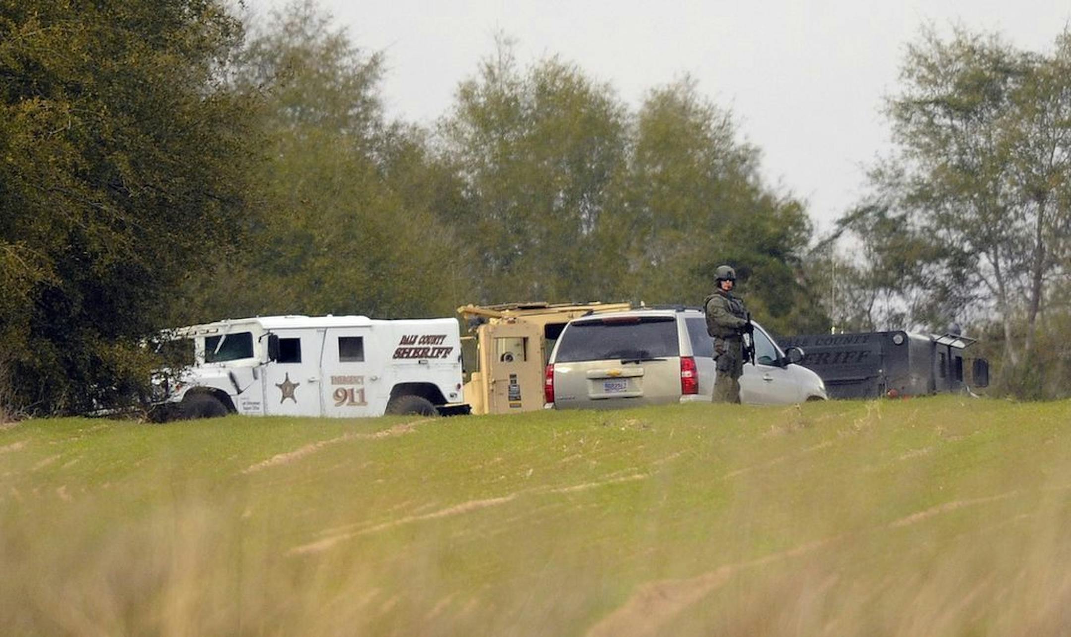 Armed law enforcement personnel station themselves near the property of Jimmy Lee Sykes, Monday, Feb. 4, 2013 in Midland City, Ala. Officials say they stormed a bunker in Alabama to rescue a 5-year-old child being held hostage there after Sykes, his abductor, was seen with a gun.