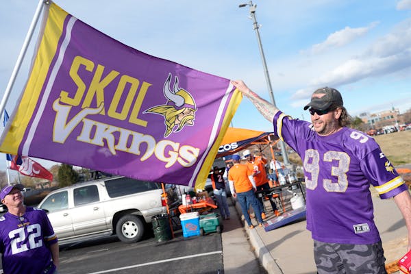 Brian Fjestad, who grew up in North Dakota as a fan of the Minnesota Vikings, holds out a flag before Sunday’s game in Denver.