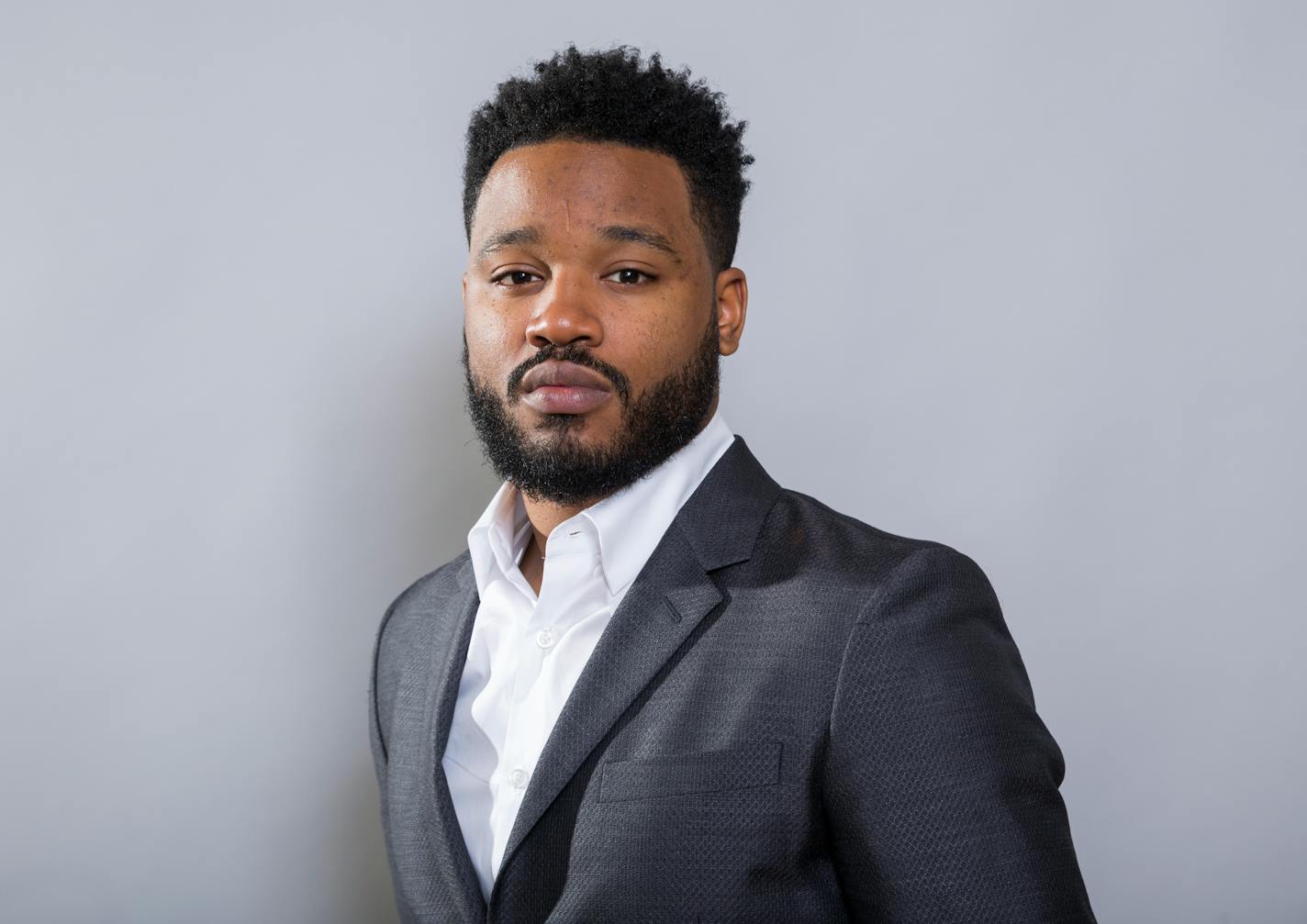 A man in a suit poses for a photo.