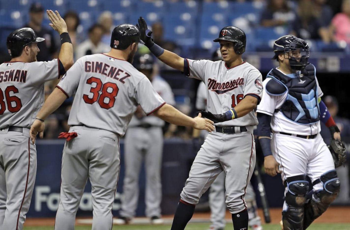 Minnesota Twins' Ehire Adrianza, second from right, celebrates with Robbie Grossman, left, and Chris Gimenez, second from left, after Adrianza hit a three-run home run off Tampa Bay Rays starting pitcher Blake Snell during the second inning of a baseball game Wednesday, Sept. 6, 2017, in St. Petersburg, Fla. Looking on is Rays catcher Jesus Sucre, right.