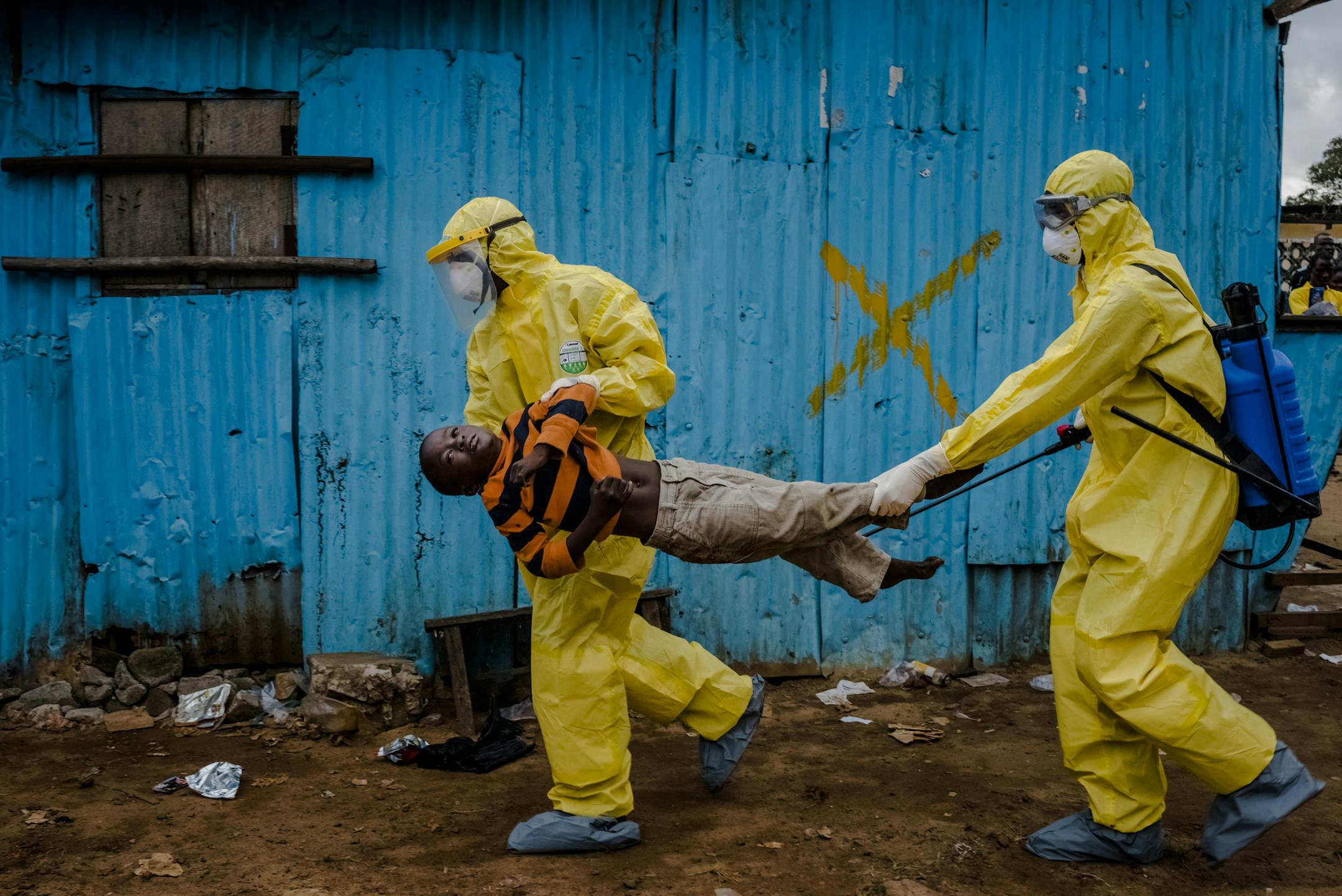 Medical staff carry James Dorbor, 8, suspected of having Ebola, into a treatment facility in Monrovia, Liberia, Sept. 5, 2014. Ebola ‚Äî the reality and the hysteria over it ‚Äî is having a serious economic impact on Guinea, Liberia and Sierra Leone, three nations already at the bottom of global economic and social indicators. (Daniel Berehulak/The New York Times)