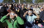 A crowd wears protective glasses as they watch the beginning of the solar eclipse from Salem, Ore., Monday, Aug. 21, 2017. (AP Photo/Don Ryan)