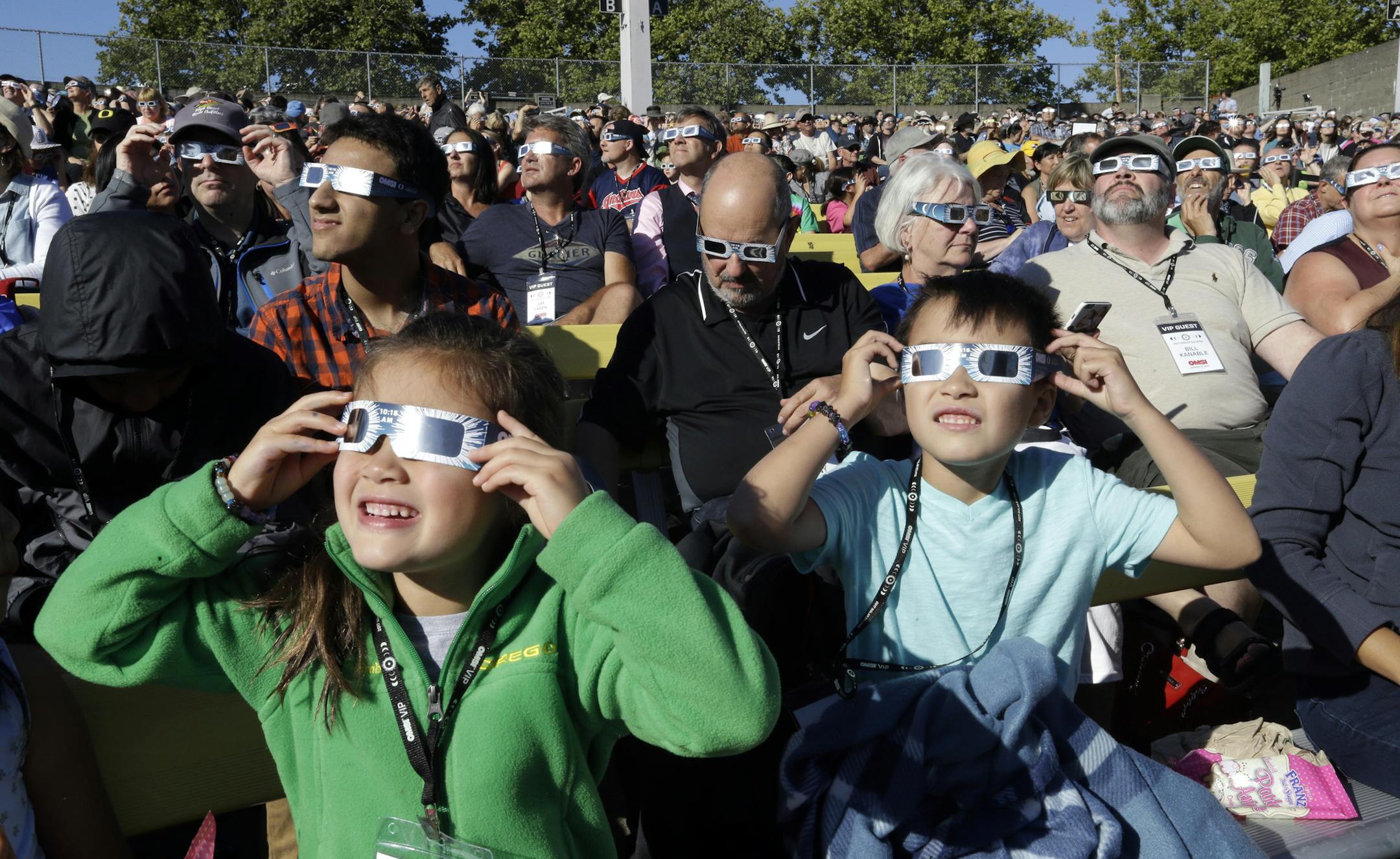 A crowd wears protective glasses as they watch the beginning of the solar eclipse from Salem, Ore., Monday, Aug. 21, 2017. (AP Photo/Don Ryan)