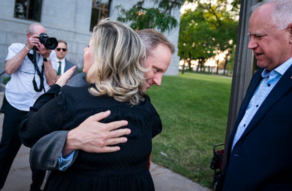 Gwen Walz got a hug from Secretary of State Steve Simon after Gov. Tim Walz, right, handed the signed education budget law to him outside the Capitol.