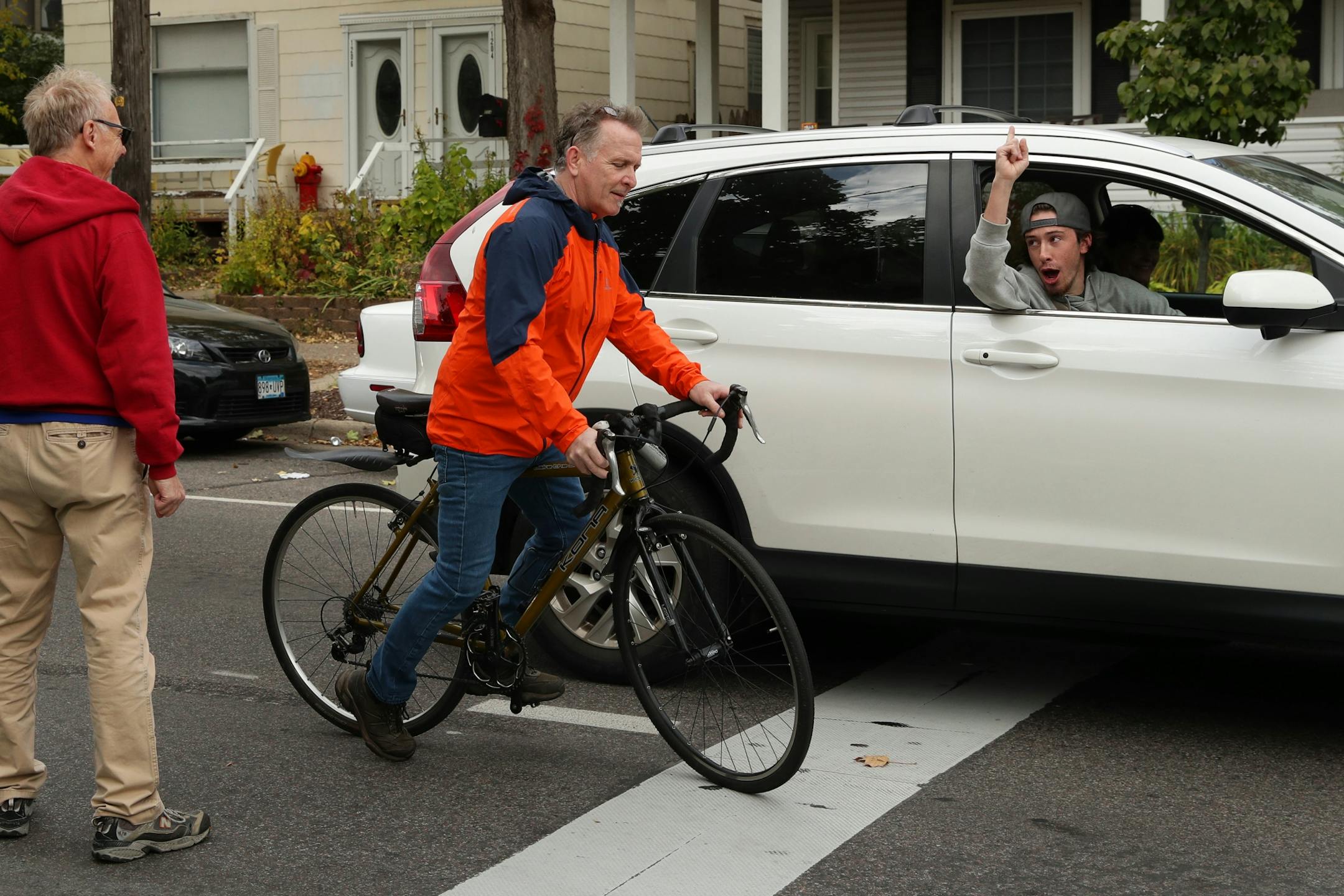 A man in a a car yelled at Chris Morris, center, who was protesting against bike lanes while riding a bike, that Minneapolis is now behind Portland for the most bike friendly city as a group protest against bike lines through the Uptown neighborhood.