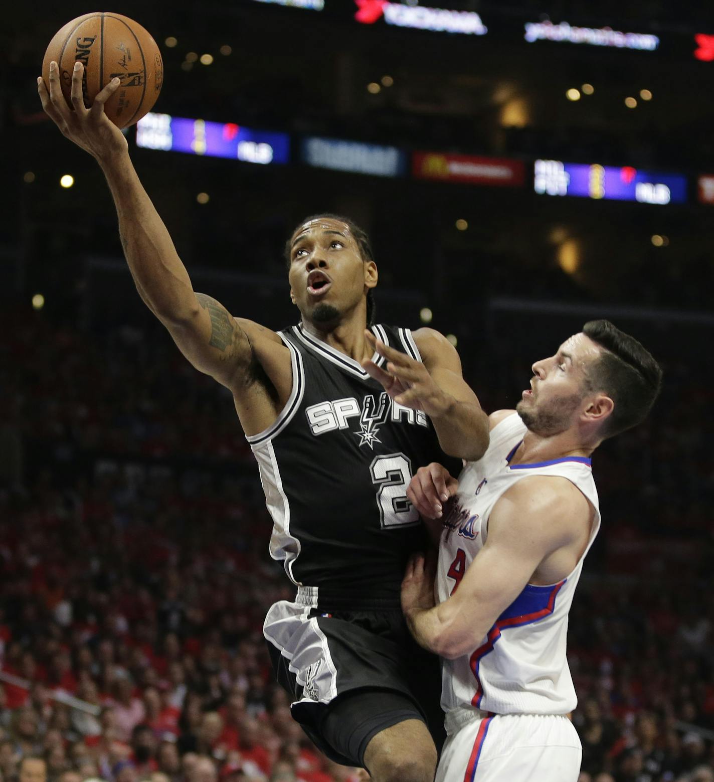 San Antonio Spurs forward Kawhi Leonard, left, drives to the basket past Los Angeles Clippers guard J.J. Redick during the first half of Game 1 of a first-round NBA basketball playoff series in Los Angeles, Sunday, April 19, 2015. (AP Photo/Chris Carlson)