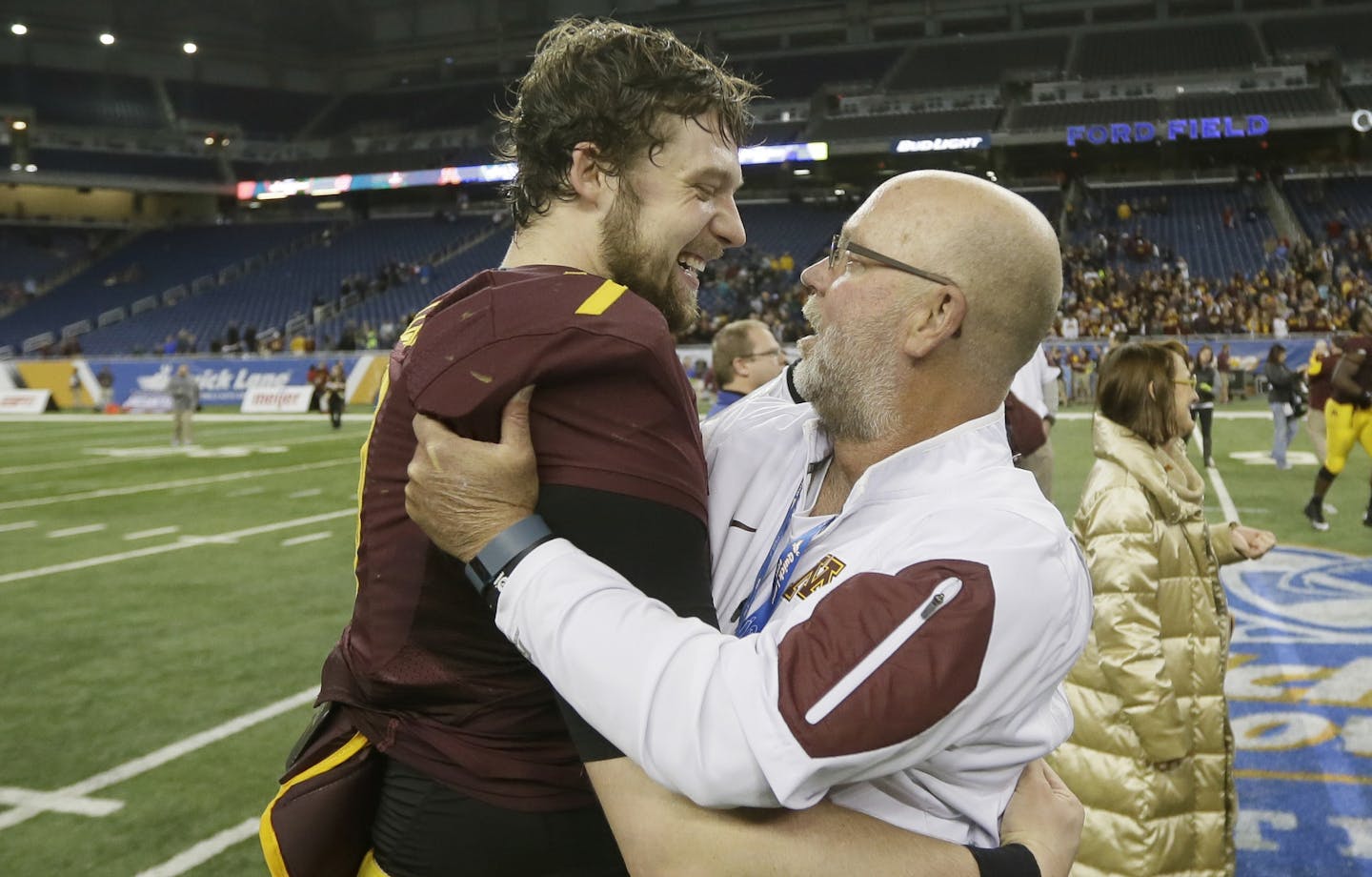 Minnesota quarterback Mitch Leidner, left, hugs former head coach Jerry Kill after the Quick Lane Bowl NCAA college football game against Central Michigan, Monday, Dec. 28, 2015, in Detroit. Minnesota defeated Central Michigan 21-14. (AP Photo/Carlos Osorio)