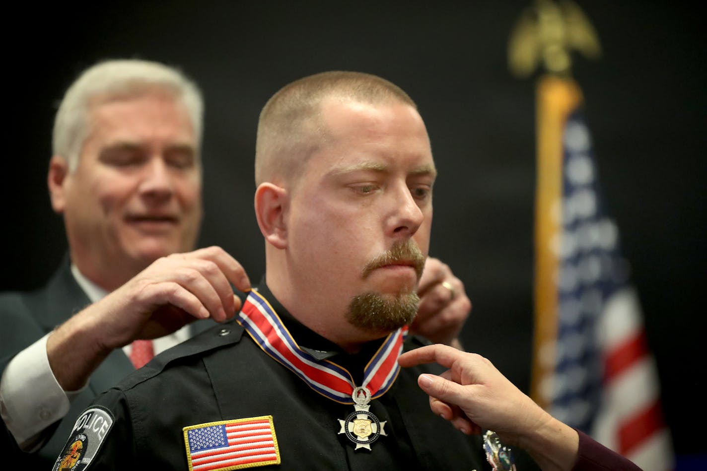 U.S. Senator Amy Klobuchar, right, partially visible and U.S. Rep. Tom Emmer present the Congressional Badge of Bravery to Jason Falconer, the Avon police officer who stopped an attacker who stabbed 10 people at a St. Cloud mall during a ceremony Thursday, April 5, 2018, at the St. Cloud Police Station in St. Cloud, MN.